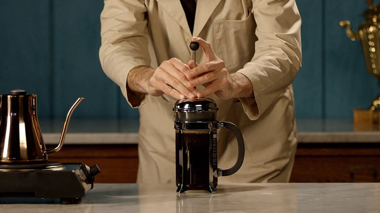 Person making coffee using a French press in a kitchen setting
